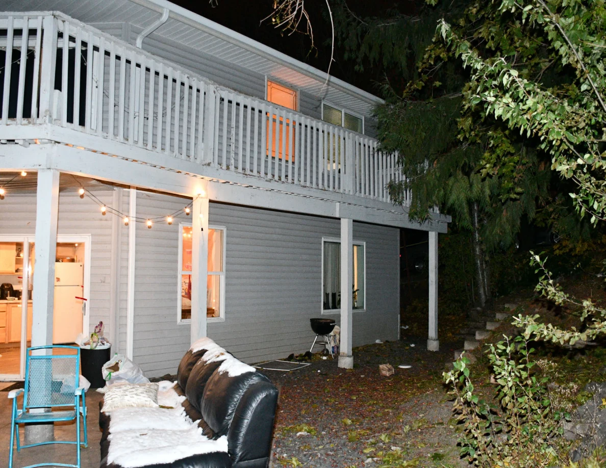 Patio sofa, folding chair and barbecue grill beneath rear balcony.