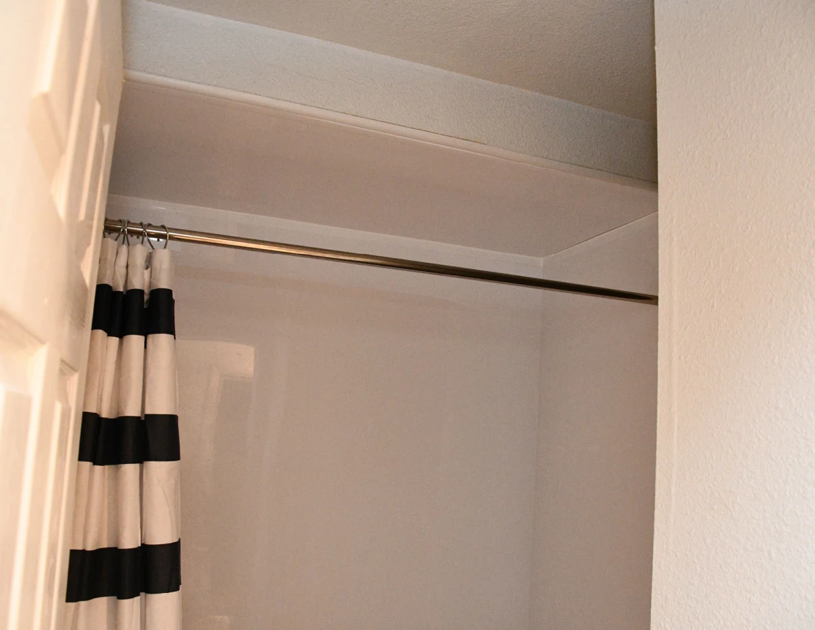 Shower curtain rod and upper bathtub surround.