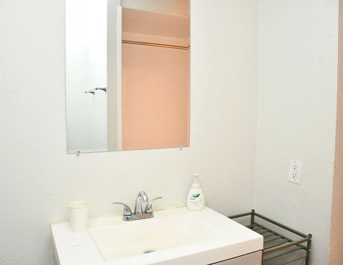 Bathroom sink and mirror reflecting the doorway.
