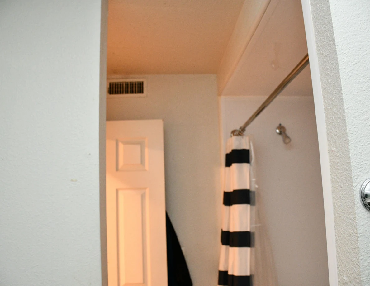 Upper bathroom doorway, curtain rod and shower head.