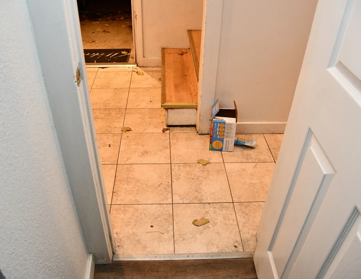 View from bathroom to tiled entryway and bottom of stairs.