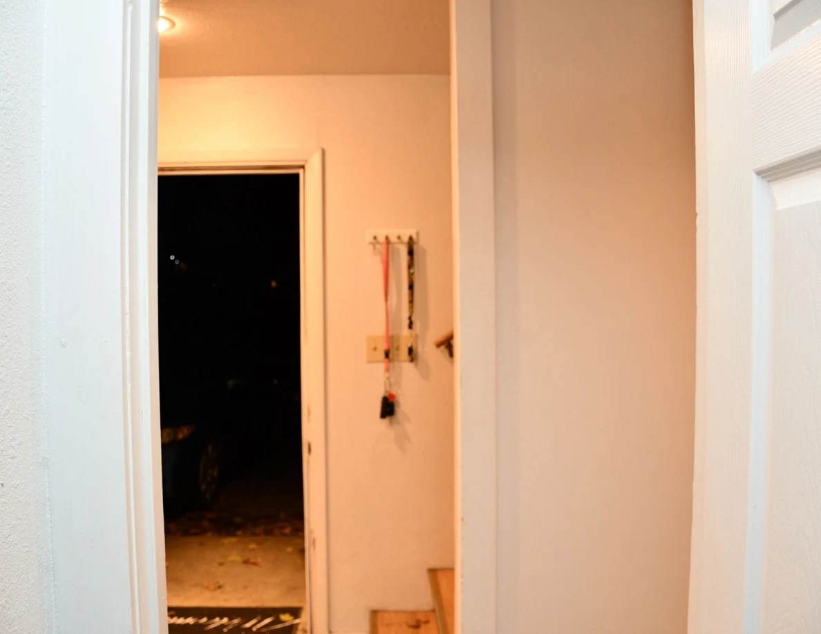 Open exterior doorway beside hooks with hanging straps.
