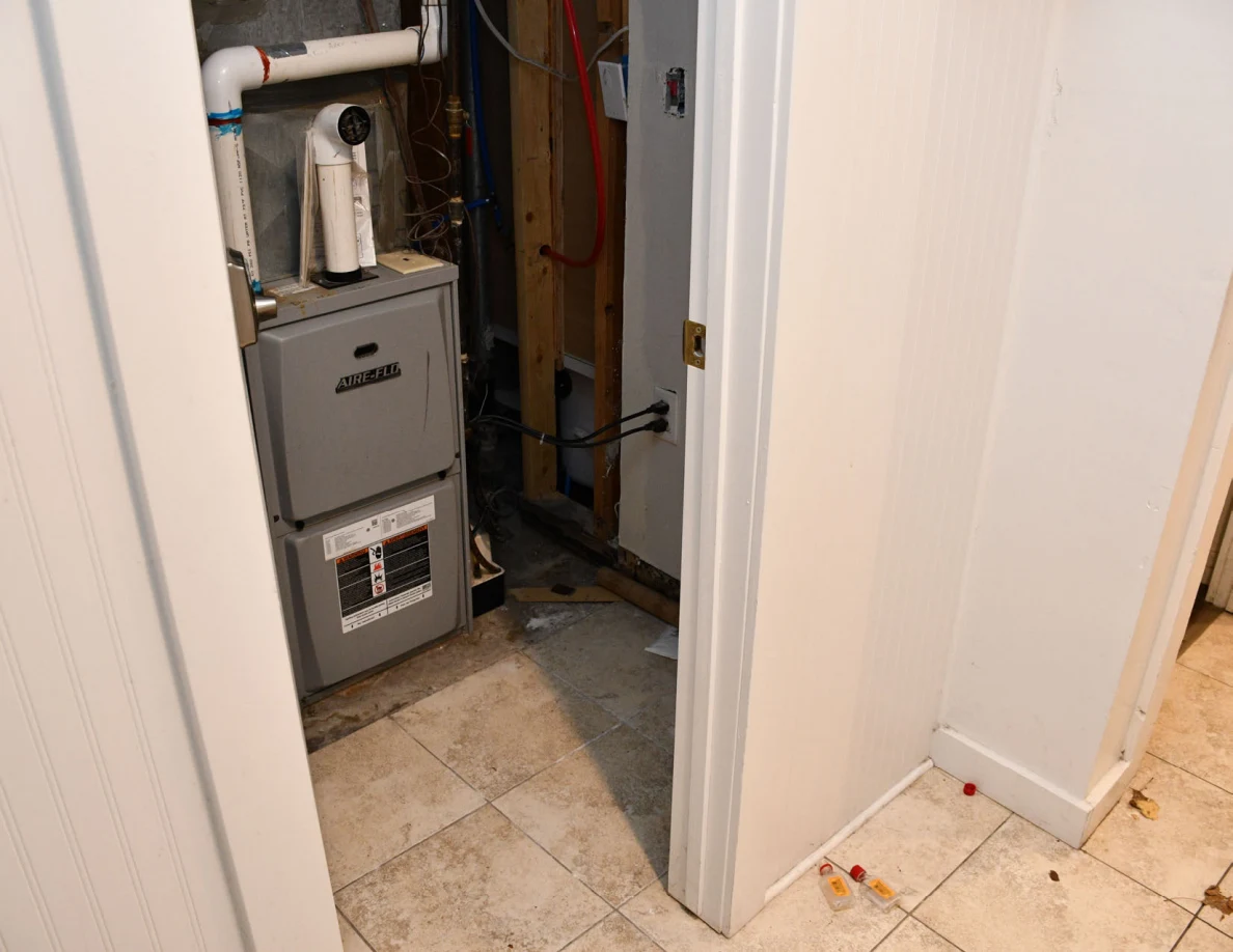 Utility closet containing a furnace and pipes.