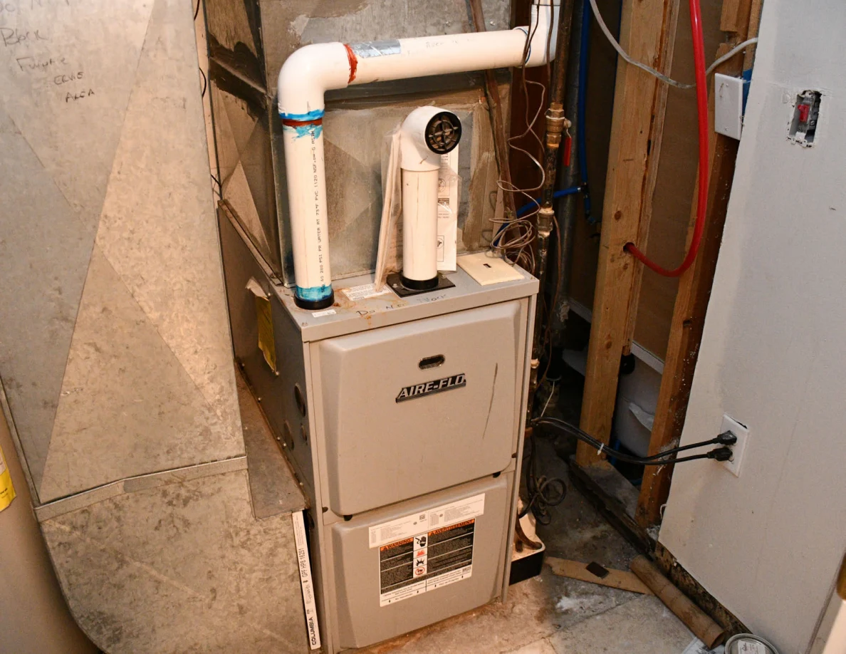 Furnace, white pipes, ducts and exposed utility wiring.