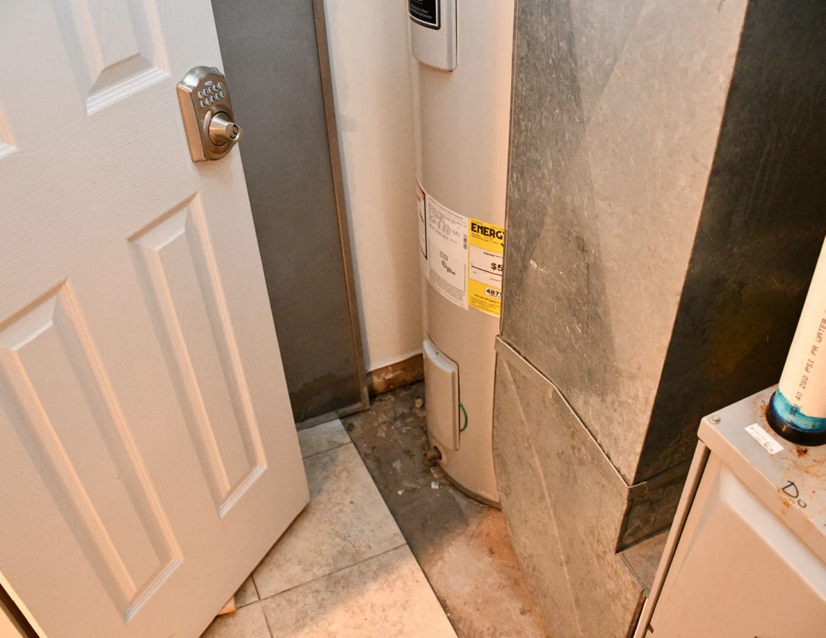 Water heater and metal duct beside open door.