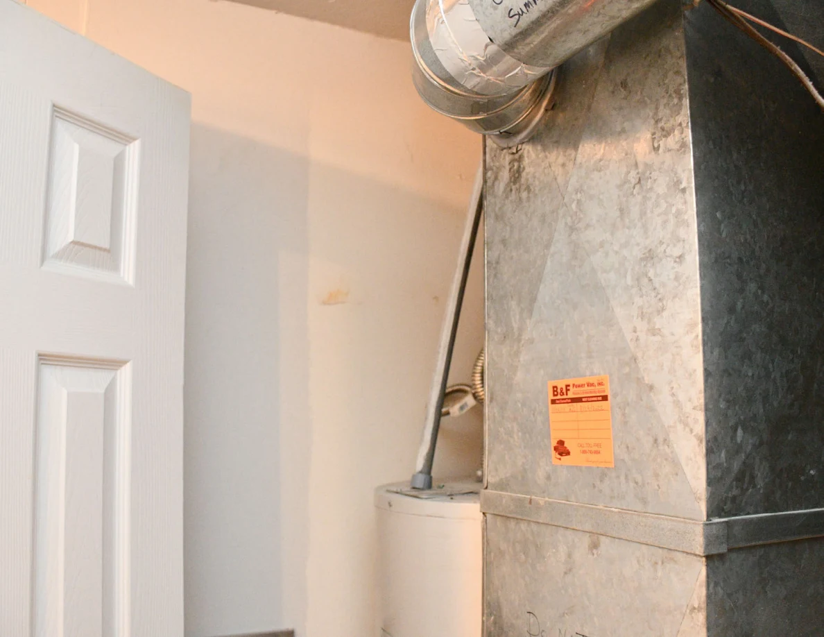 Metal ductwork with a small orange label beside a door.