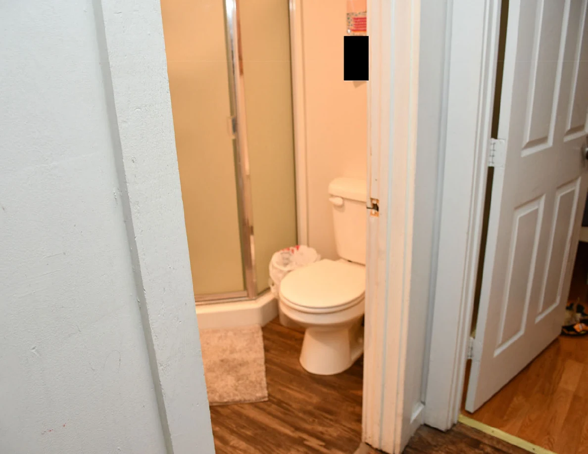 Bathroom doorway showing closed toilet and glass shower enclosure.