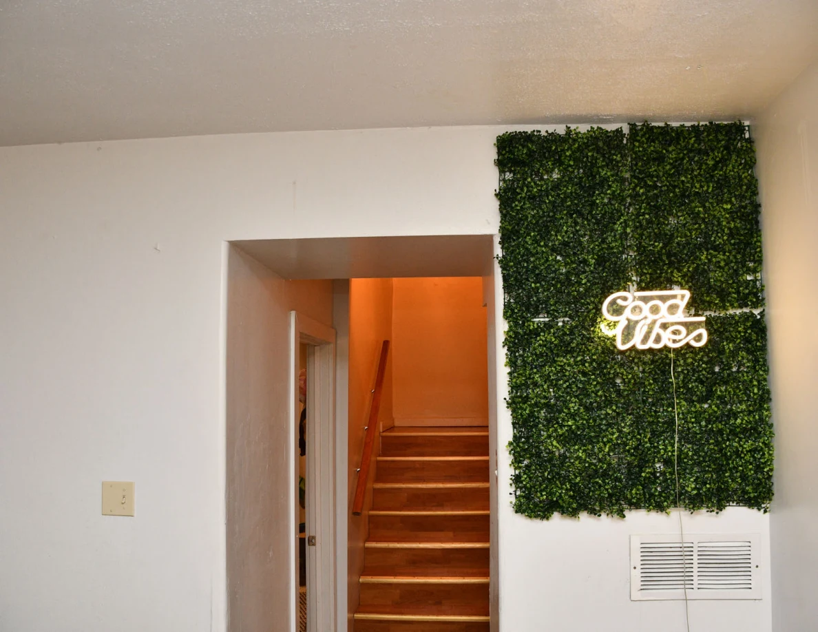 Upper doorway beside foliage panel with illuminated Good Vibes sign.