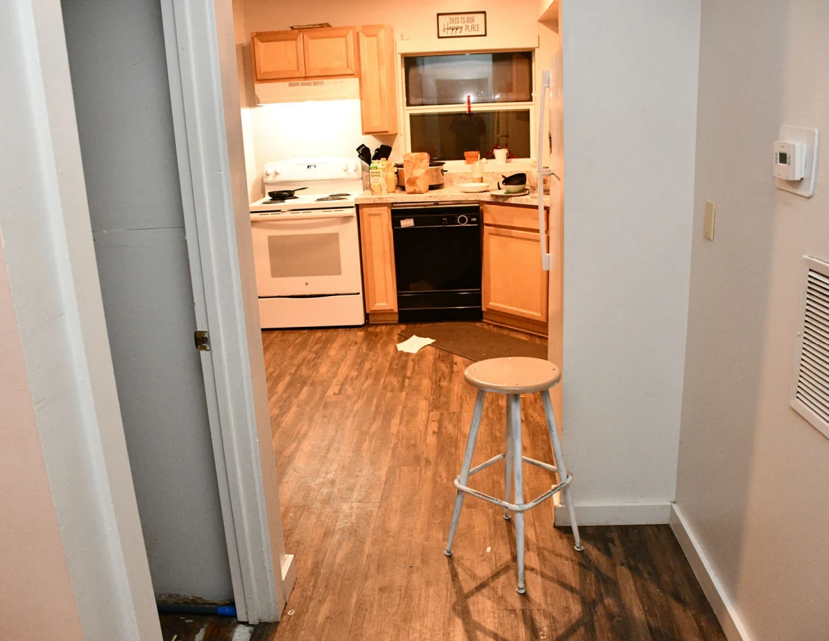 Hallway stool in front of kitchen with stove, dishwasher and cabinets.