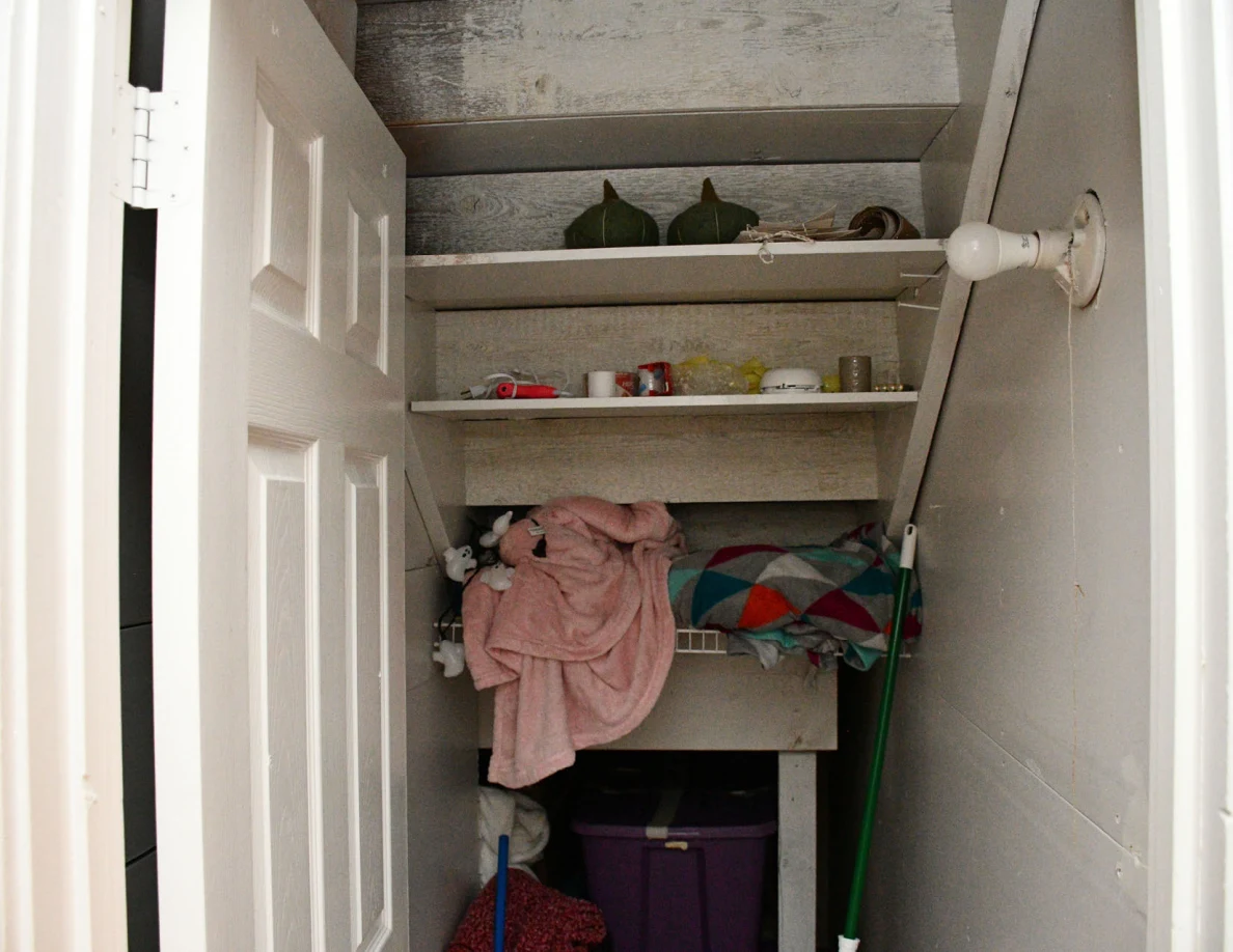 Open cupboard shelves containing containers and clothing.