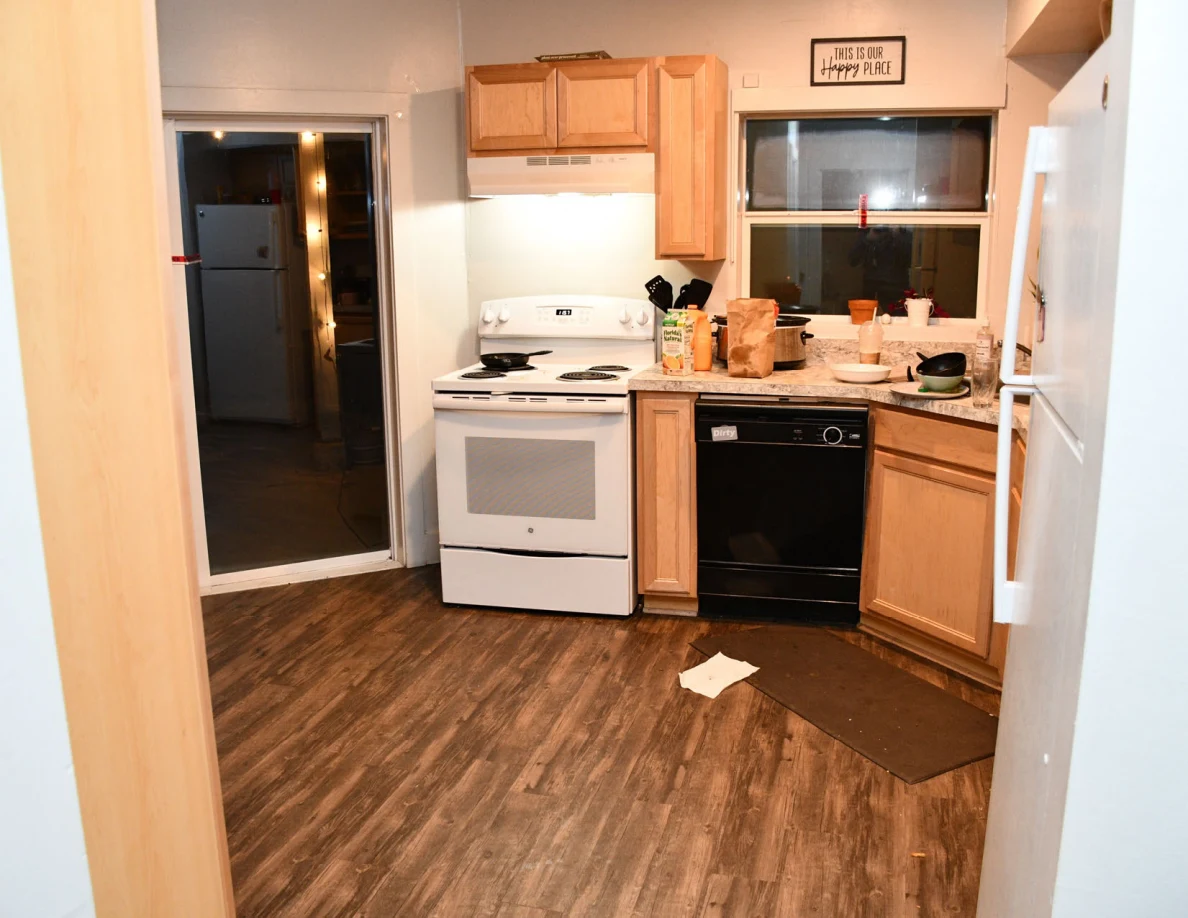 Kitchen with stove, dishwasher, cabinets and sliding glass door.
