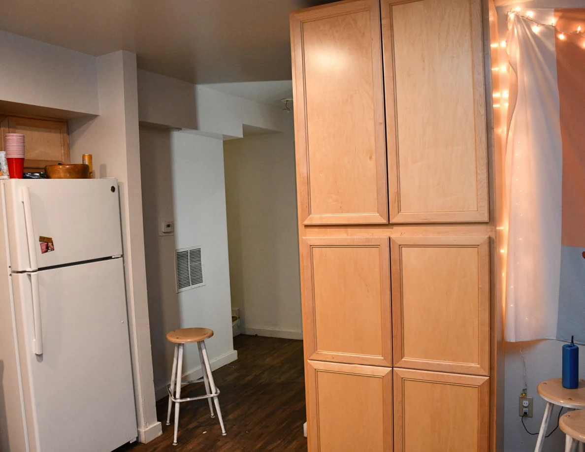Tall kitchen cabinet beside refrigerator and hallway.