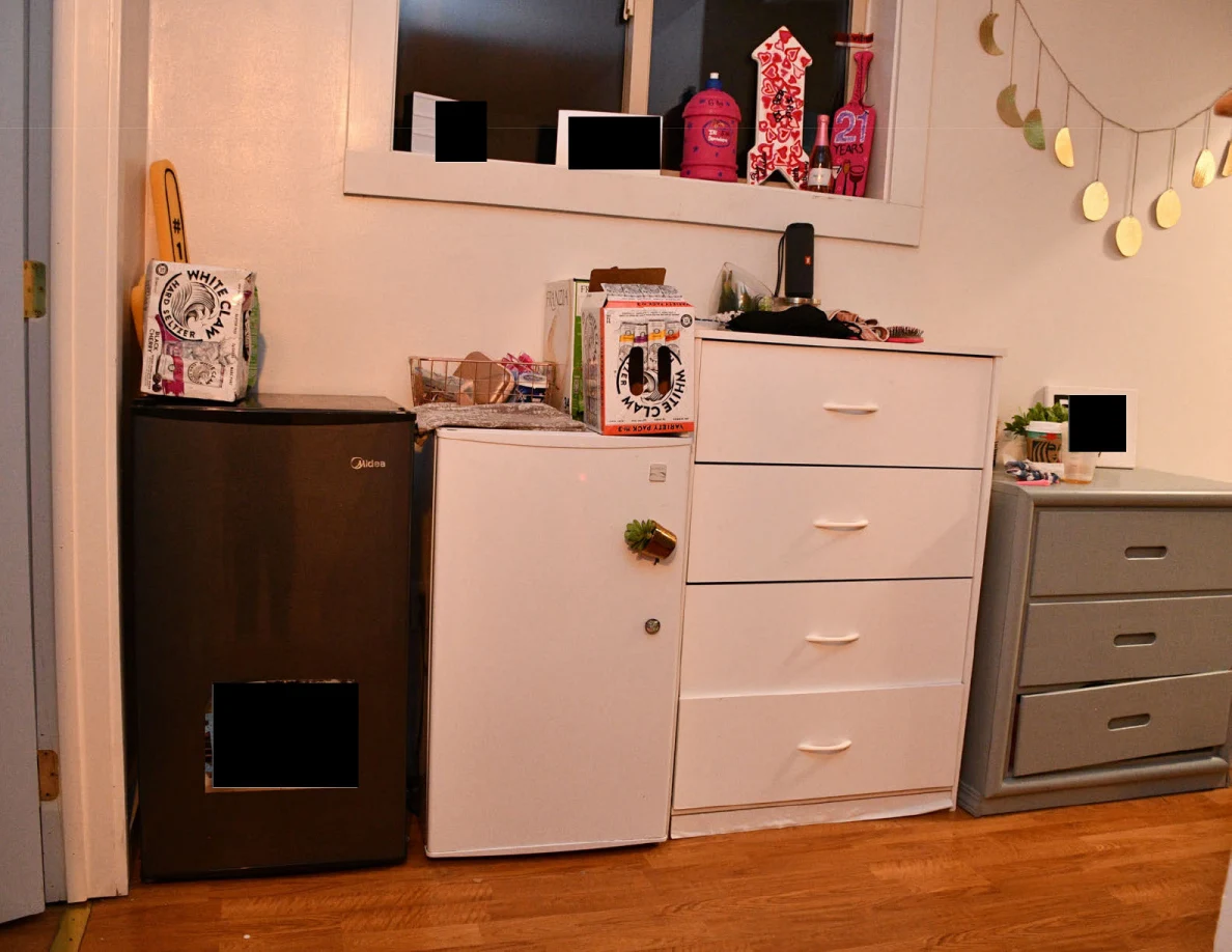 Compact refrigerators and drawer units beneath a window and moon decoration.