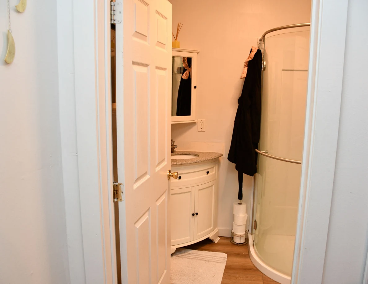 Bathroom doorway showing corner sink and curved shower enclosure.
