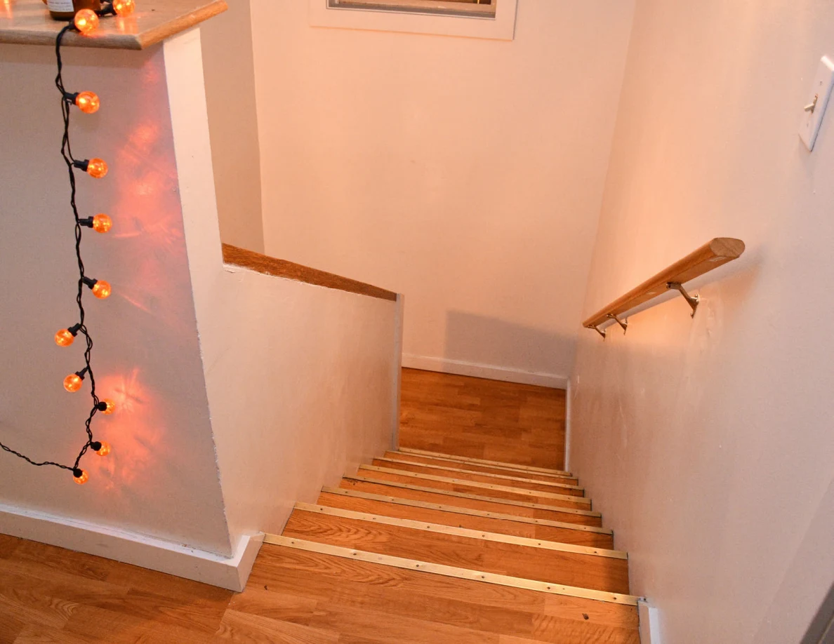 View down wooden stairs beside orange string lights.