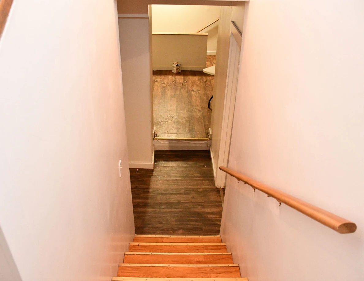 View down staircase toward hallway and room beyond.