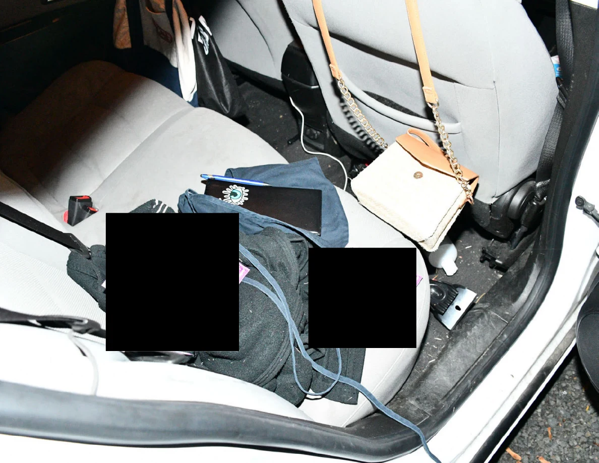 Car rear seat with bags and partly redacted items.