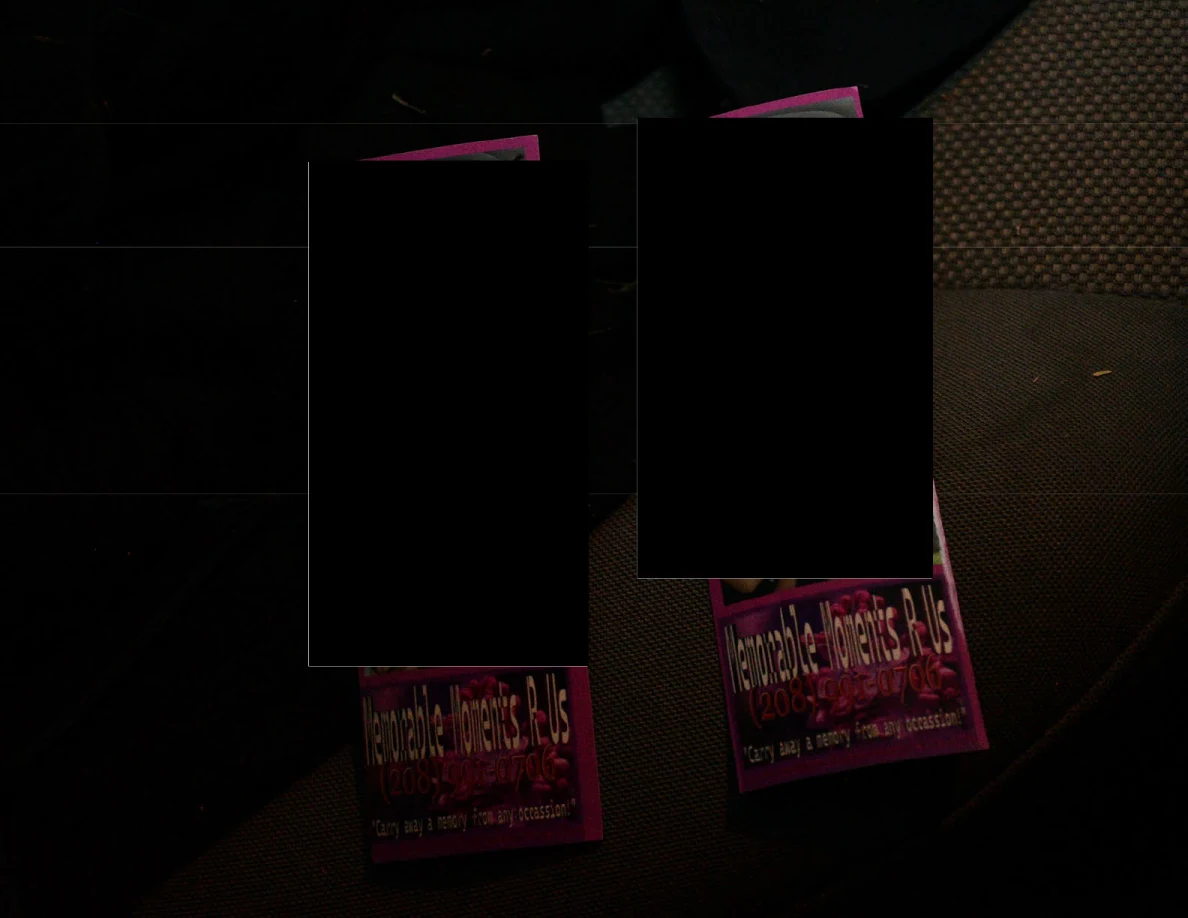 Partially redacted rectangular printed items on a dark vehicle seat.
