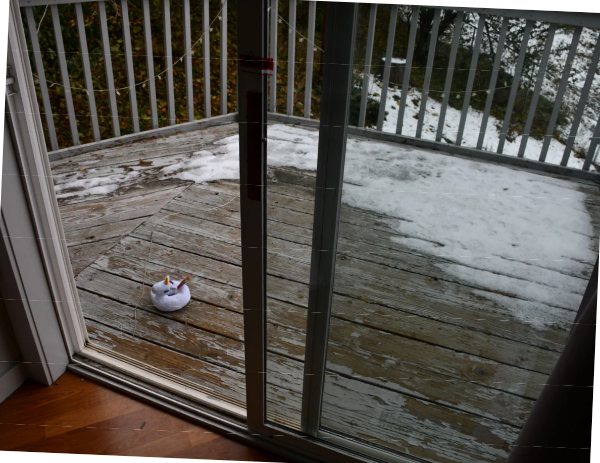 Sliding glass door opening toward a snow-covered wooden balcony.