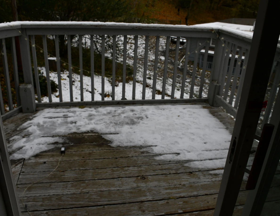 Snow-covered balcony boards and railing.