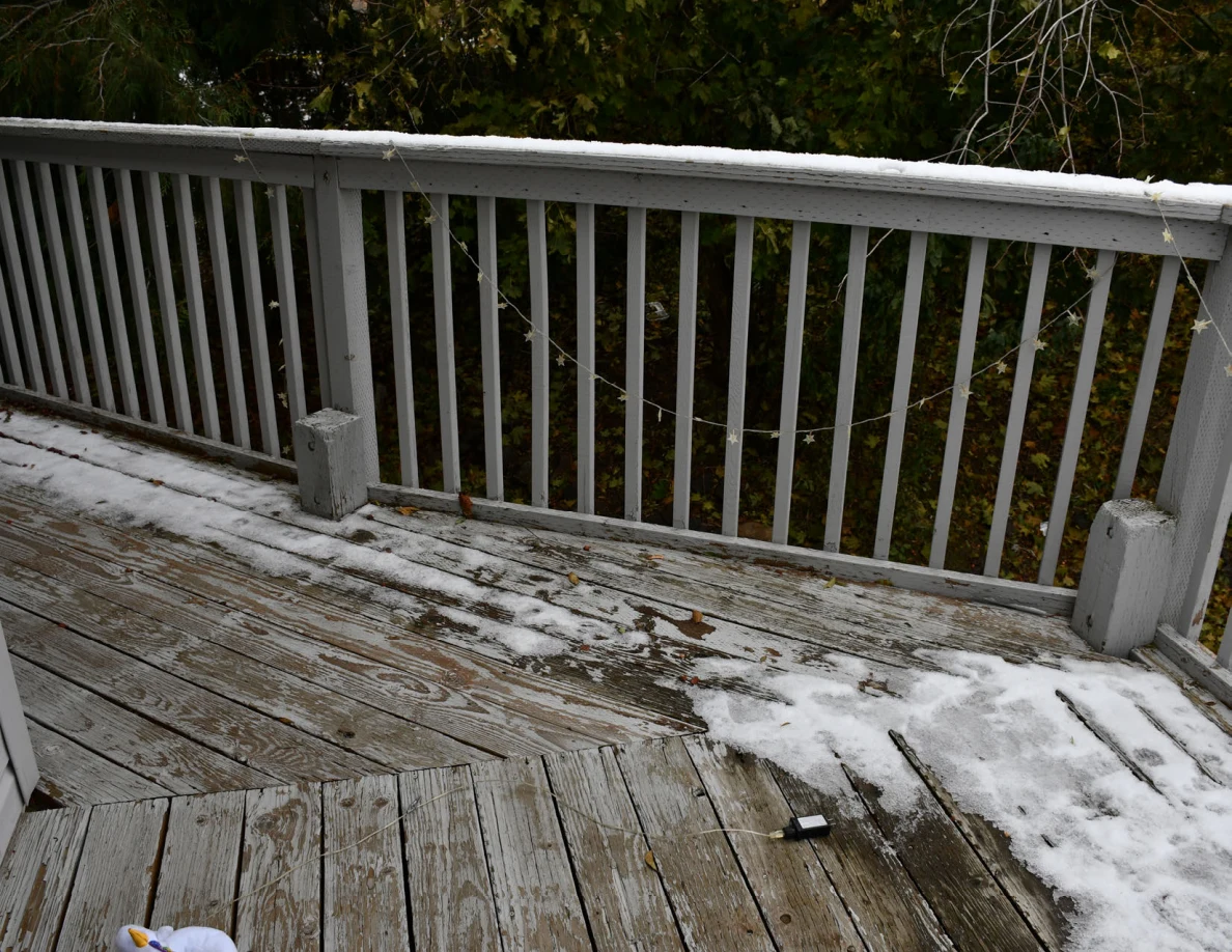 Balcony boards, railing and patchy snow.