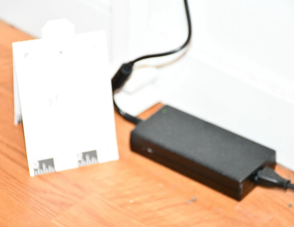 Close view of black electronic device with connected cables beside a reference card.