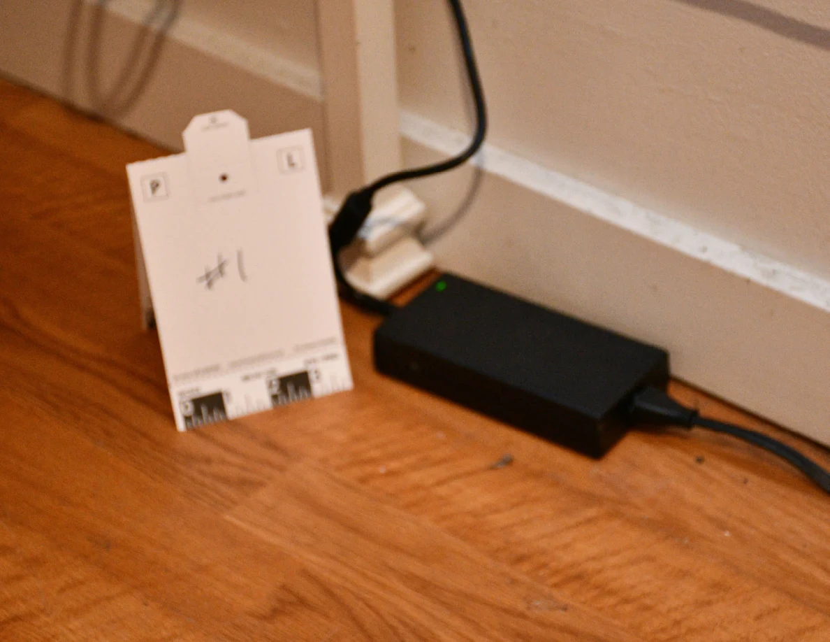 Black electronic device and cables beside reference card marked #1.