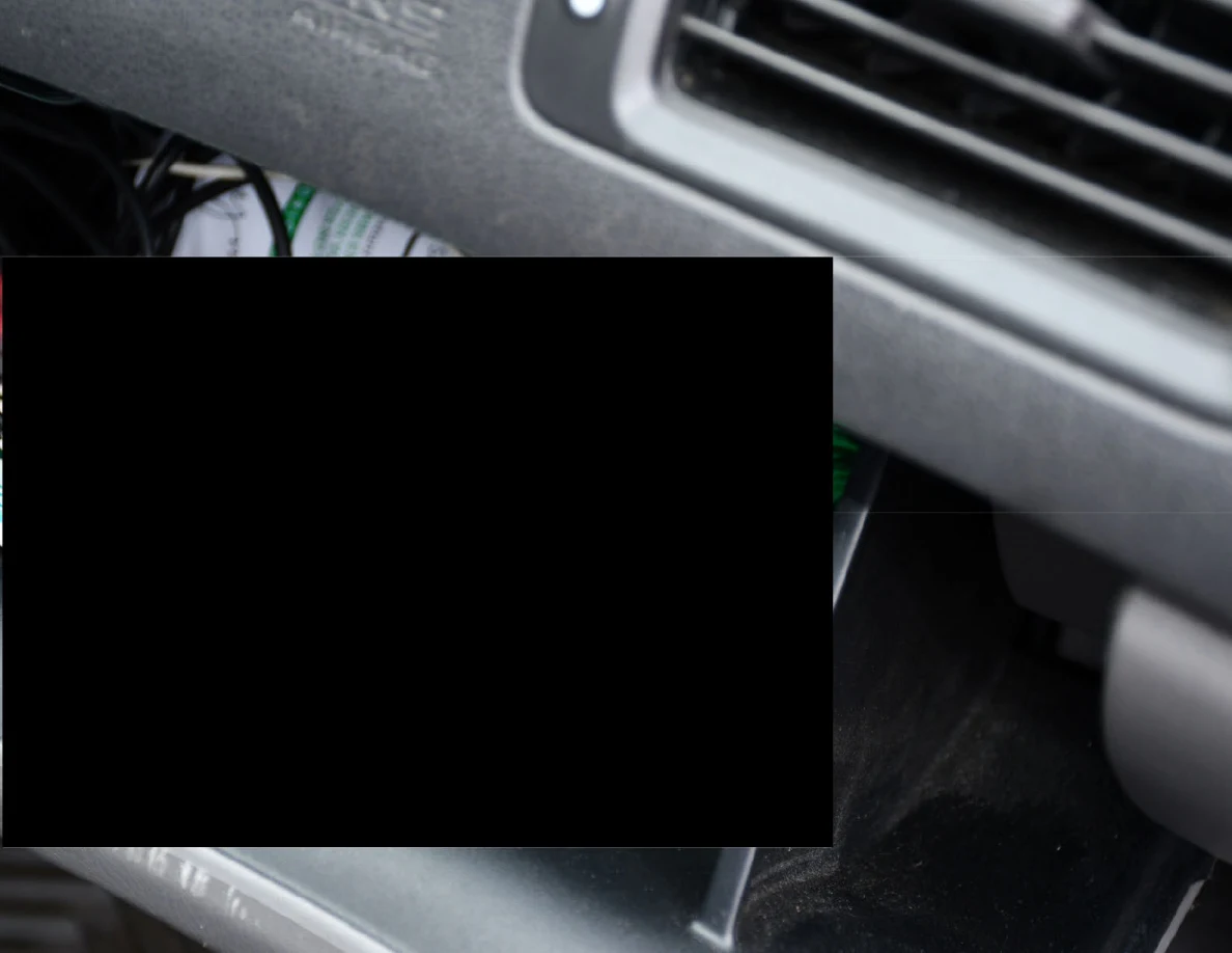 Close view of an open glove compartment with a large redaction.
