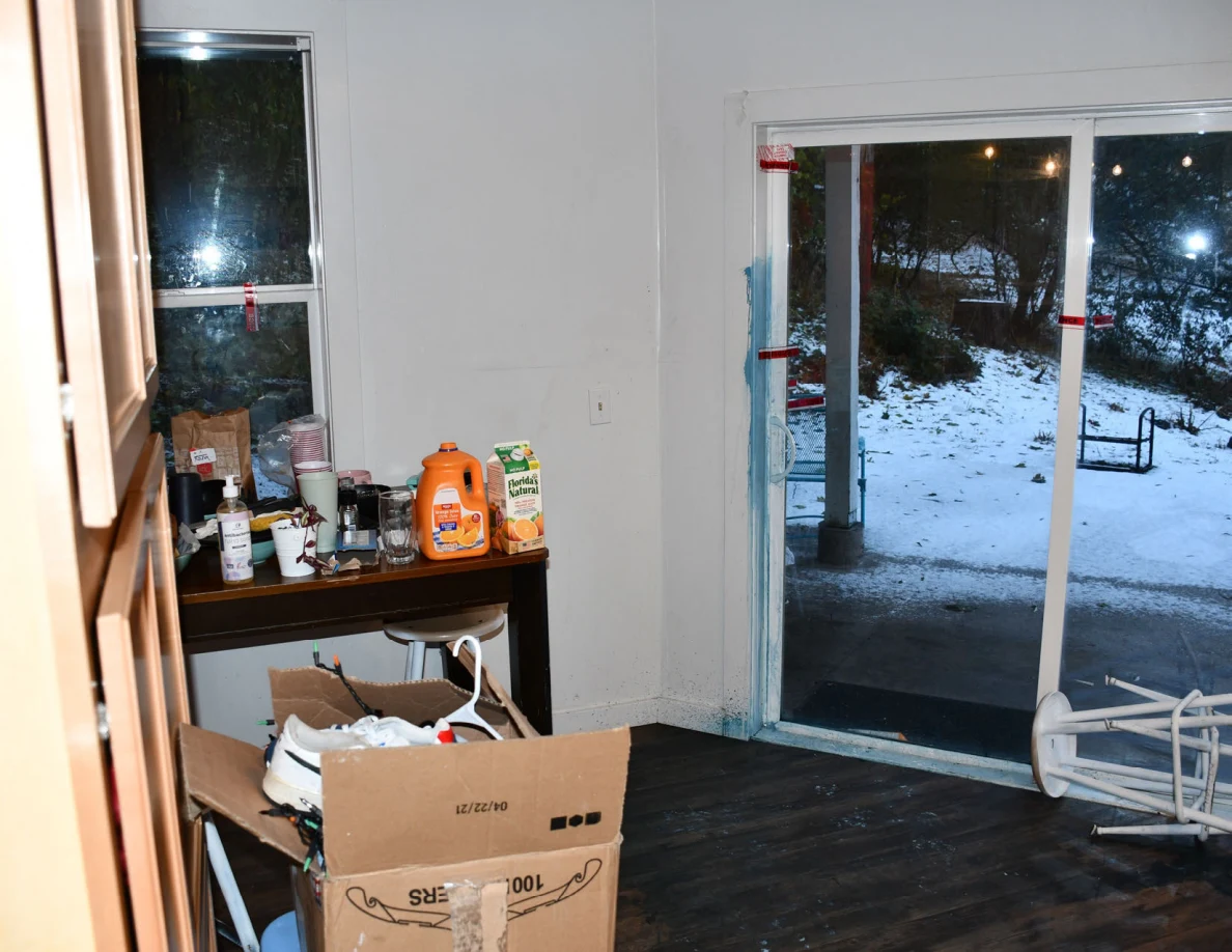 Kitchen sliding glass door, table with household items and cardboard box.