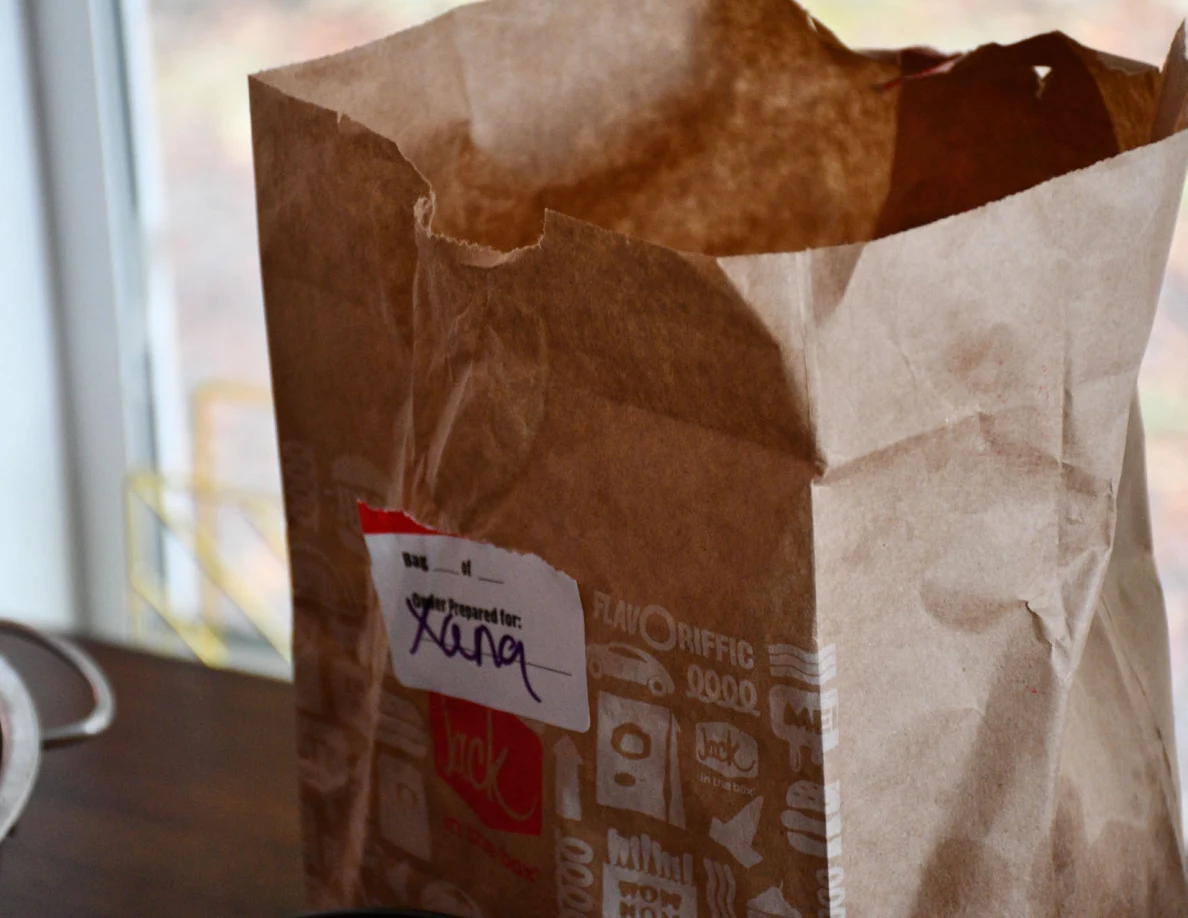 Close view of paper takeaway bag with handwritten label reading Xana.