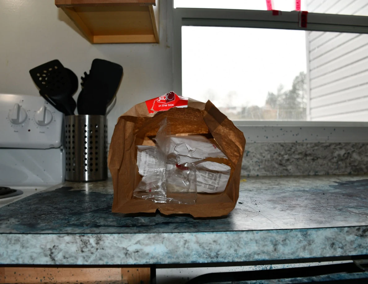 Opened paper takeaway bag on kitchen counter with wrapped contents visible.