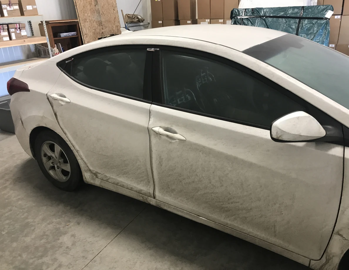 Side windows and doors of dirty white sedan indoors.