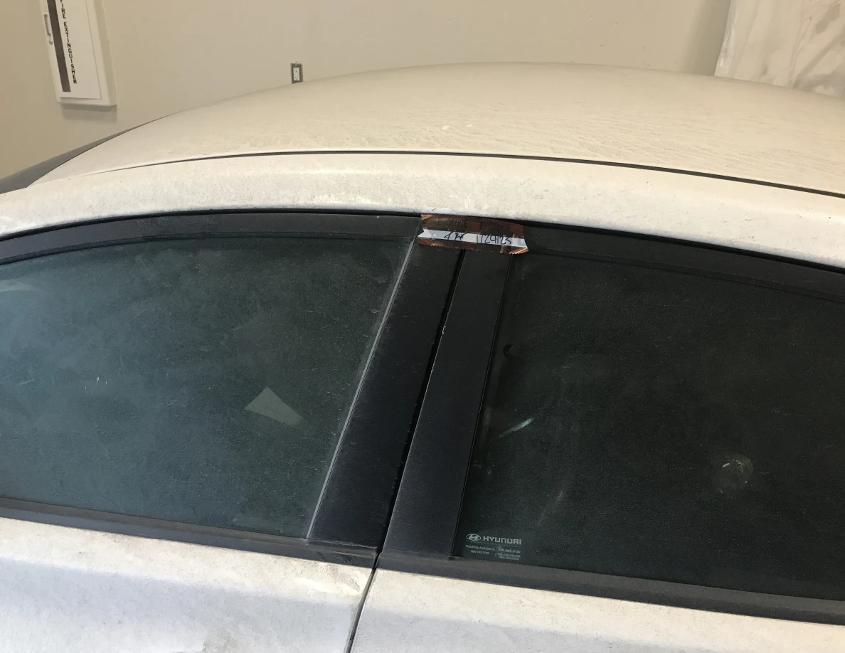 Close view of car roofline and dark side windows with tape near door frame.