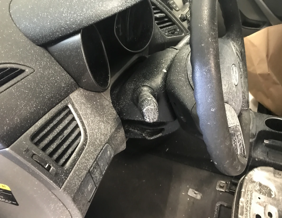 Close view of car dashboard and steering wheel with pale surface speckling.