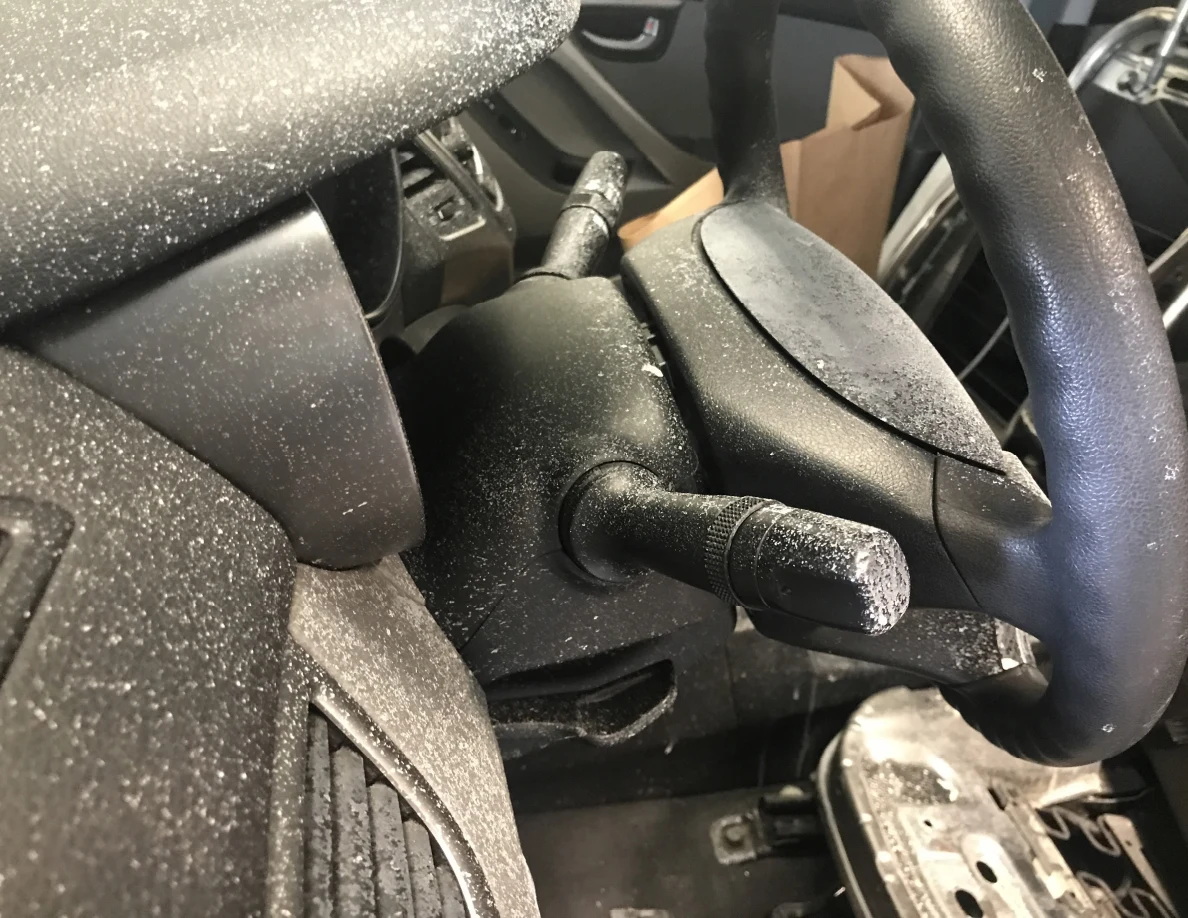 Close view of steering-column controls and steering wheel with surface speckling.
