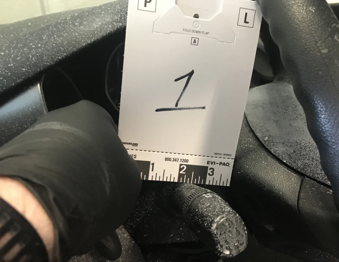 Gloved hand holding reference card 1 beside steering-column control.