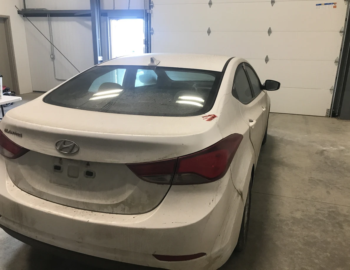 Rear of white Hyundai sedan facing a garage door.