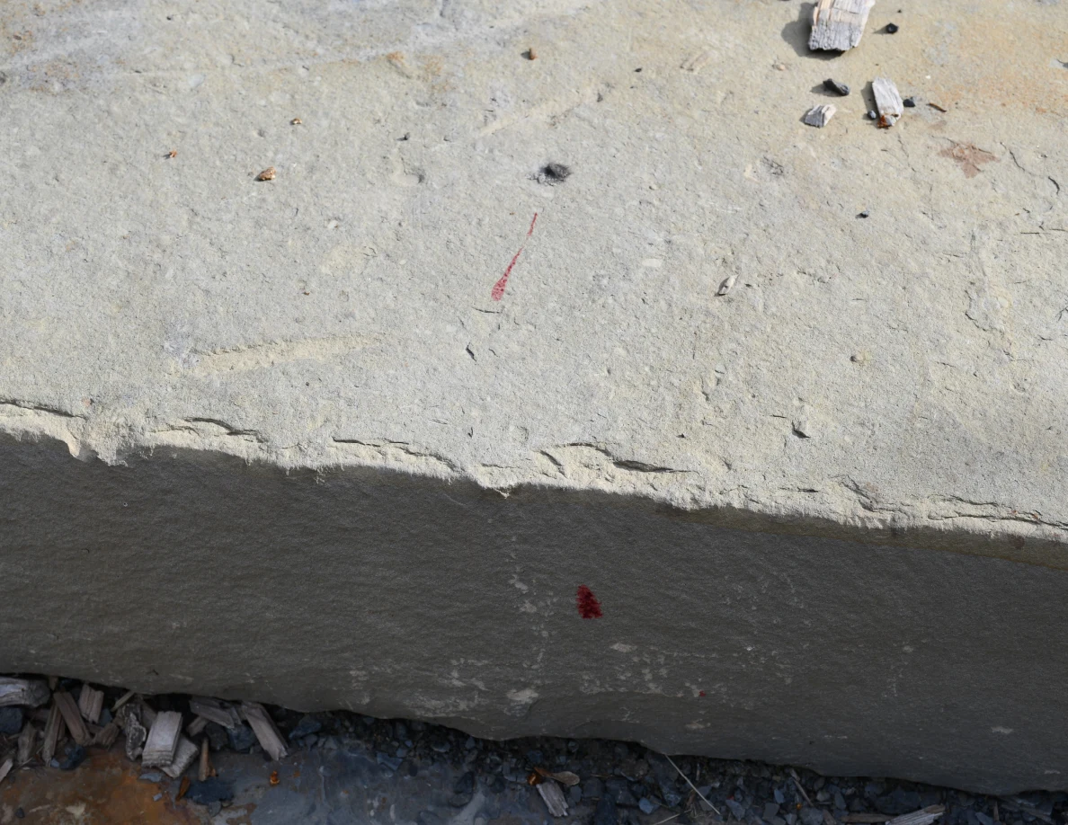 Stone step with reddish marks on its top and front face, with small debris nearby.