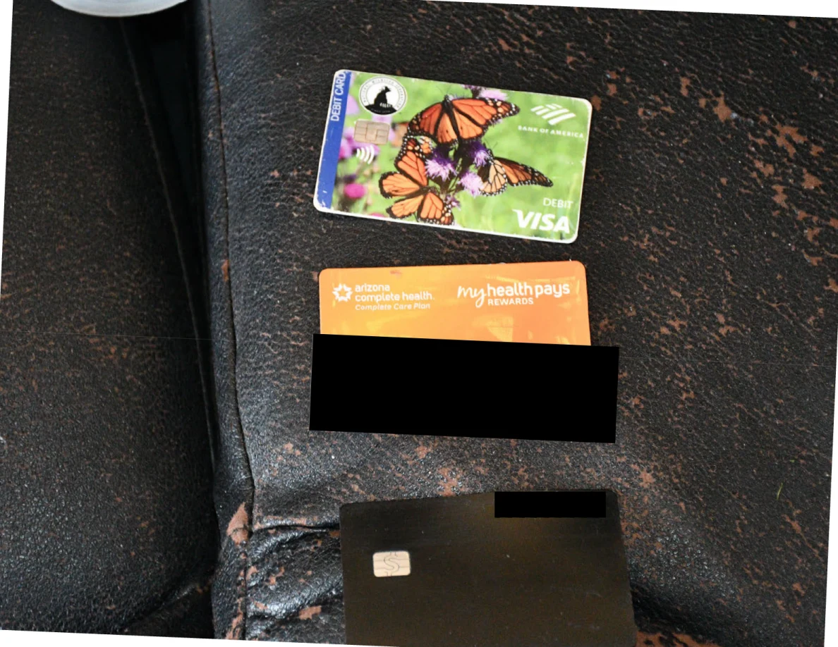 Three payment or rewards cards laid on worn black upholstery, with identifying information covered by black redactions.