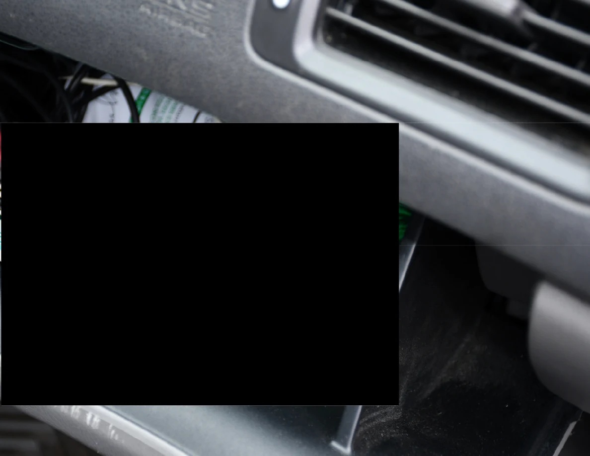 Close view of a vehicle glove compartment and dashboard vent, with most of the lower image blacked out.