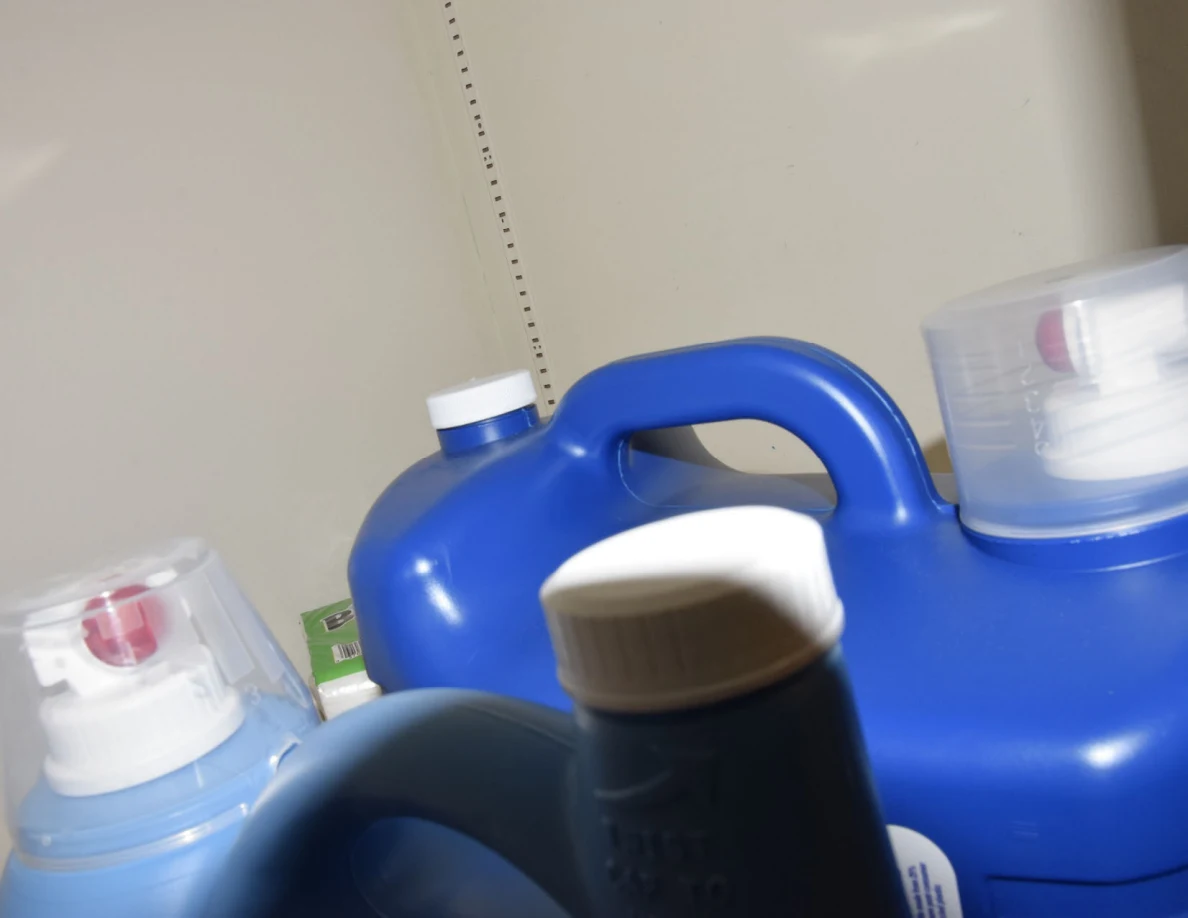Close view of blue laundry-product jugs and pump containers on a shelf.