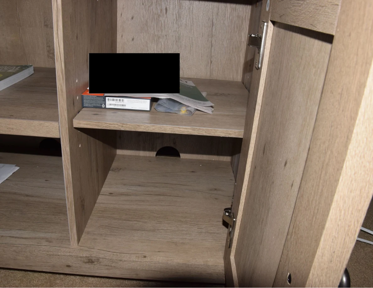 Open cabinet compartment containing small books and papers partly obscured by a black redaction.