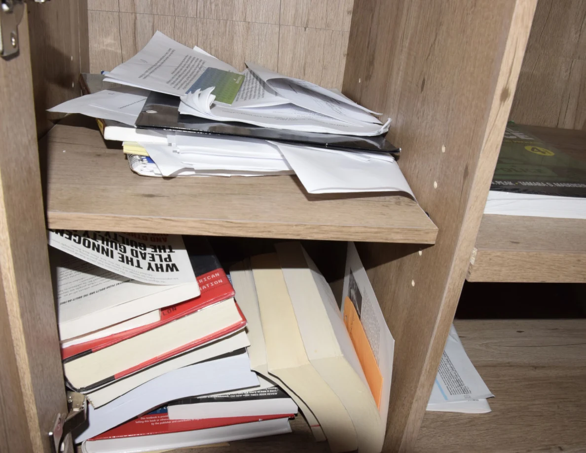 Close view of stacked papers and books inside an open wooden cabinet.