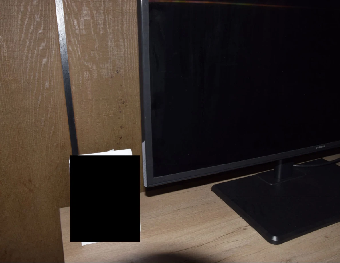 Television base and a paper standing on a wooden cabinet, with the paper blacked out.