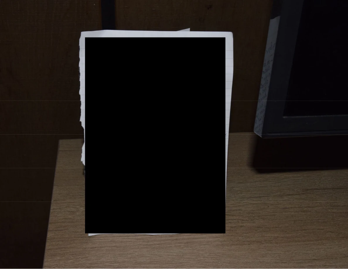 Close view of a paper on a wooden cabinet, almost entirely covered by a black redaction.