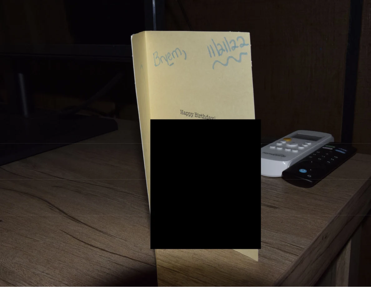 Back or inside panel of a yellow greeting card with blue handwriting and a large black redaction.