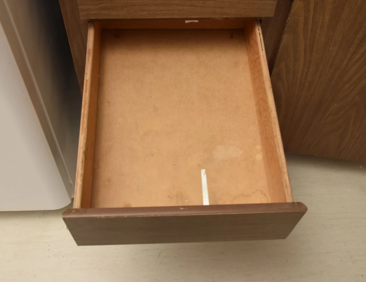 Nearly empty wooden drawer with a narrow white strip near the front.