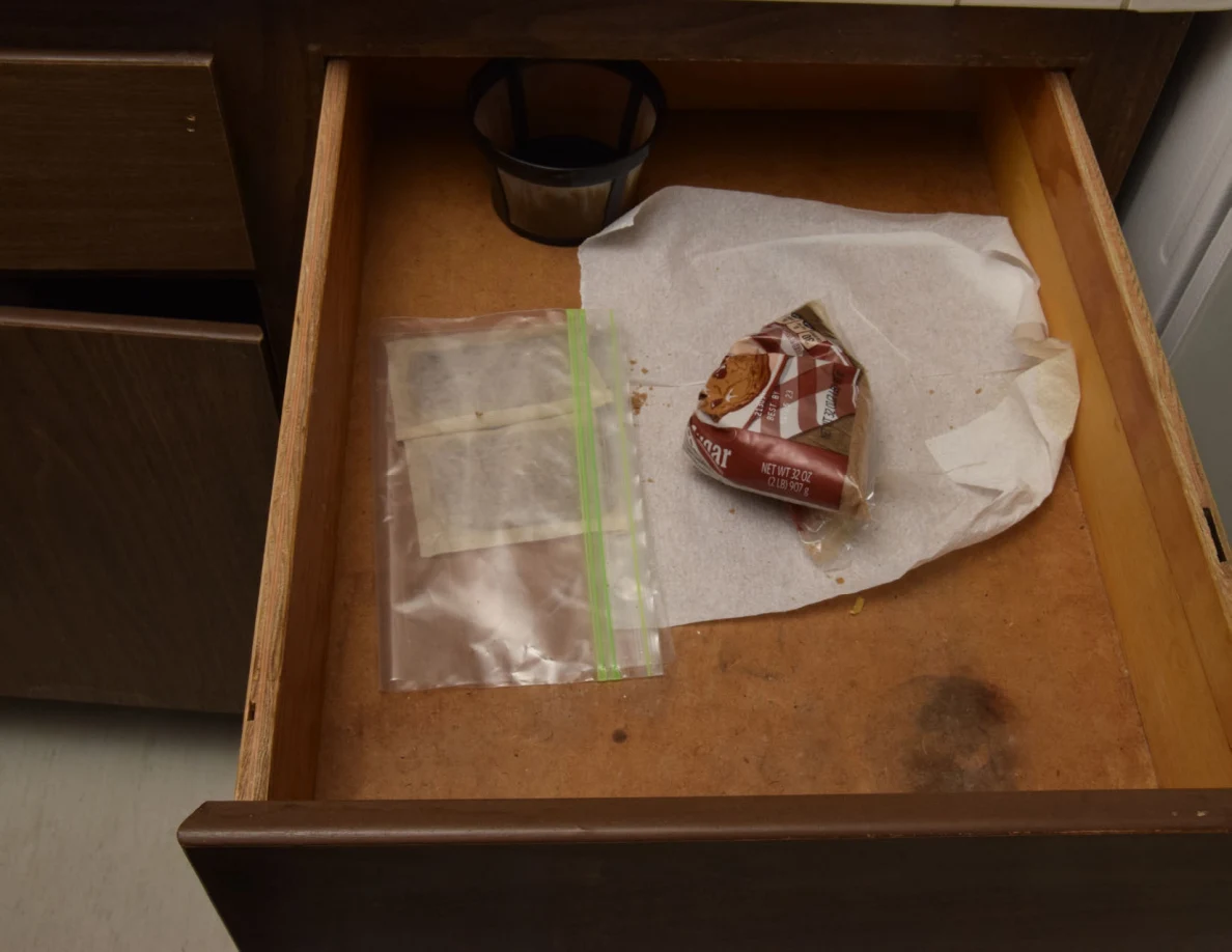 Open kitchen drawer with a coffee filter basket, paper towels, a resealable bag and a crumpled food packet.