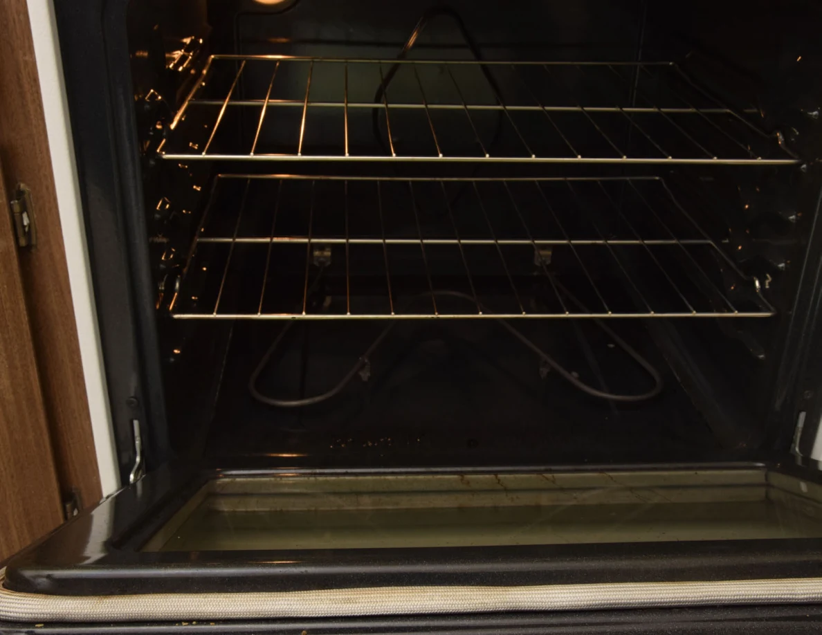 Open oven interior showing two wire racks, a heating element and interior light.