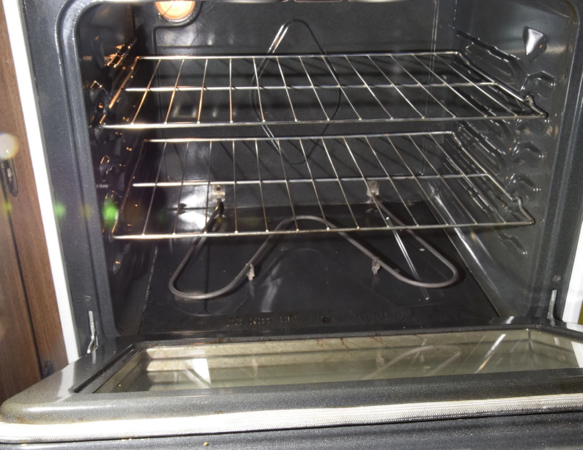 Bright view of an open empty oven with two wire racks and a lower heating element.